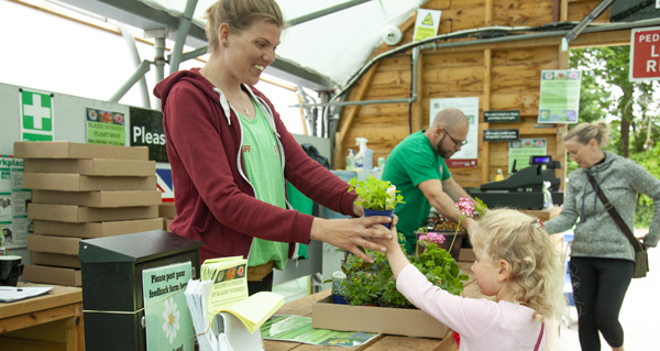 Lady in a shop giving a plant to a child